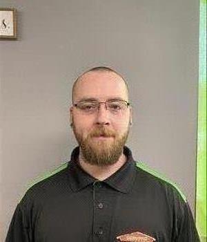 Image of male employee with black polo and green background